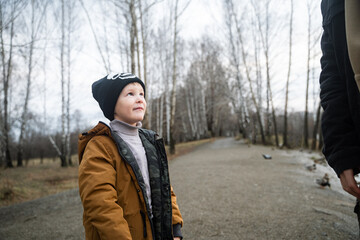 The boy looks up very attentively, the young dad explains to the child, brings up on the street, tells what is possible and what is not, conversation with his son