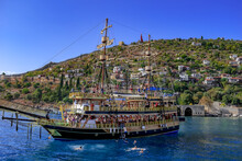 Tourist Pirate Schooner On The Background Of The Old City In Alanya (Turkey). Vintage Wooden Ship With Two Masts In The Mediterranean Sea Off The Coast Of The Peninsula With An Ancient Fortress