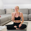 © kasto - Beautiful blonde woman doing home workout indoors. Woman practice yoga at home. Fit girl using workout tutorials for healthy active lifestyle. Woman using quarantine for home workouts. Stretching