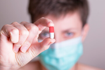 woman in a protective mask with a pill