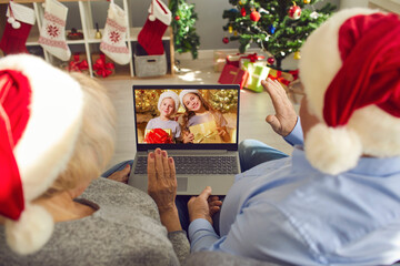 Grandparents in Santa hats video calling their little grandchildren on Christmas Day