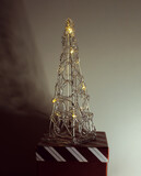 Fototapeta Boho - Souvenir christmas electric tree from transparent plastic with illumination stand on big red gift present box, holiday minimalistic theme