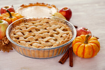 Two traditional American Thanks Giving pies with apples, mini pumpkins & cinnamon sticks. Homemade fruit tarts baked to golden crust. Close up, copy space, top view, background.