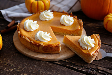 Wall Mural - Traditional thanksgiving food on wooden table. Orange delicious homemade pumpkin pie with crust and decorative items. Thanksgiving table setting concept.Top view, close up, copy space, background.