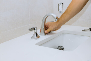 Wall Mural - Plumber hands at work in a bathroom, plumbing repair service the faucet of a sink