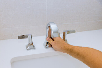 Wall Mural - Male hands plumber fixing a faucet of a sink in bathroom