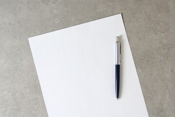 Template of white paper with a ballpoint pen on light grey concrete background. Concept of new idea, business plan and strategy, empty space for text