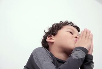 Poster - boy praying to god with hands together on white background stock photo