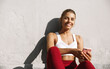 © Liubov Levytska - Sports woman sitting outdoors and listening to music from smartphone. Smiling female runner taking break from running workout