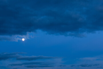 background of mystery cumulus clouds with moon on a blue sky at evening blue hour after sunset. tele