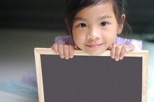 Portrait Of Cute Girl Holding Writing Slate At Home