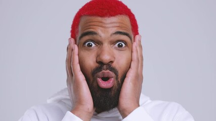 Wall Mural - Close up of shocked young bearded african american man with red hair in hoodie posing isolated on white background studio. People lifestyle concept. Looking camera say wow covering mouth with hands