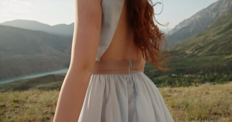 Wall Mural - Beautiful caucasian girl wearing white dress on top of a mountain. Gorgeous woman looking at camera and positively smiling 4k footage