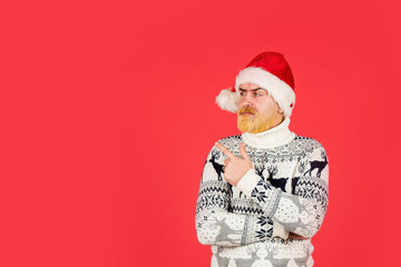 Wall Mural - bearded hipster dyed hair red background. new year party is here. copy space. christmas shopping time. mature male knitted xmas sweater. brutal man hate winter holidays. serious man santa hat