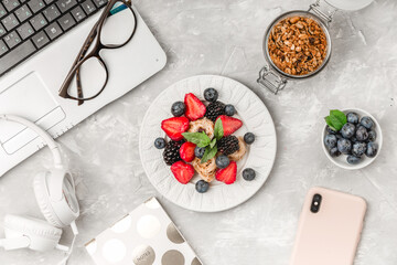 Wall Mural - Overhead view of laptop, fresh breakfast with fruit, headphones and mobile phone on white desktop table.Top view and flat lay. Woman business and breakfast concept.