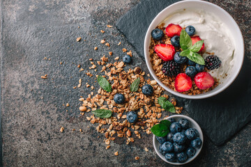 Wall Mural - Healthy breakfast with granola, yogurt, fruits, berries on dark metal background. Summer homemade breakfast.