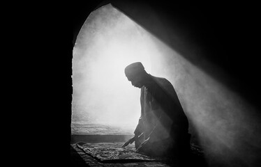 Silhouette religious of muslim male praying in old mosque with lighting and smoke background