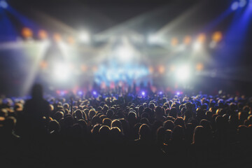 A crowded concert hall with scene stage lights, rock show performance, with people silhouette, colourful confetti explosion fired on dance floor air during a concert festival