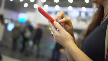 A woman in a shopping center and reads messages on her smartphone. Close-up shooting. 4K