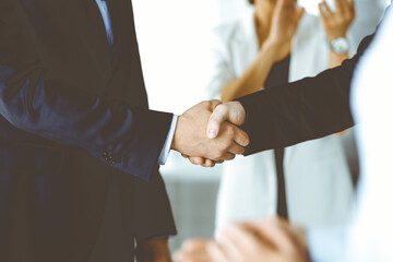 Unknown businesspeople are shaking their hands after signing a contract at meeting, close-up. Business communication concept