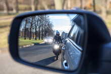 Mutual Passing, Motorcycle And Vehicle With Dazzle Lighting Overtaking The Car, View In A Side Mirror. Improper Driving Or Traffic Violation