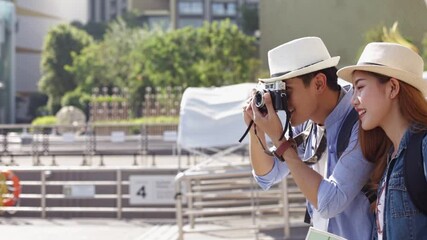 Wall Mural - Traveler Asian couple travel in riverside Bangkok, Thailand, sweet couple taking photo  spending holiday trip in sunset. Young fun happy Asian tourist backpacker travel.