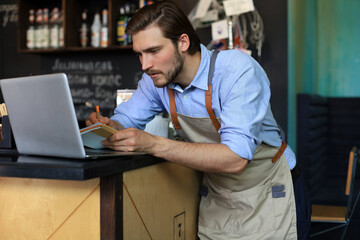 Wall Mural - Restaurant manager working on laptop, counting profit.