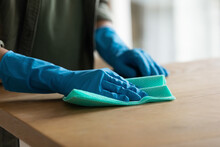 Crop Close Up Of Woman In Rubber Protective Gloves Clean Wooden Kitchen Counter Surface With Napkin. Female Housekeeper Do Home Cleaning Routine Wipe Dust From Countertop Table. Housekeeping Concept.