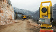 © scharfsinn86 - Theodolite (total positioning station) on a background of road construction in mountains