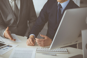 Business people using computer while working together in modern office. Unknown businessman or male entrepreneur with colleague at workplace. Teamwork and partnership concept