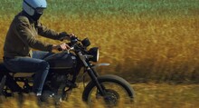 Motorcyclist Rides Through A Beautiful Field