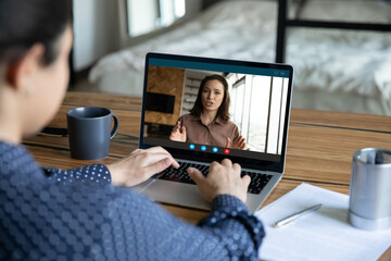 Canvas Print - Back view focused young indian mixed race woman holding video call consultation with middle aged female mentor coach, enjoying educational class or discussing working issues with boss remotely at home