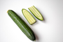 Isolated Whole And Two Halves Of A Cucumber Cut Lengthwise Close-up On A White Background