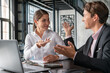 © VideoFlow - Male and female office managers smiling discussing work, man in black suit and woman in white shirt. Smiling business partners in office room sitting to table with laptop, concept of work