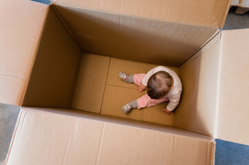 Wall Mural - One year old baby girl sitting in a big paper box.