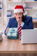 © Elnur - Young male employee working in the office at Christmas Eve