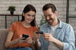 © fizkes - Smiling millennial caucasian couple involved in online shopping, entering payment information from credit bank card in mobile application, satisfied with quick money transfer, modern tech concept.