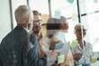 © Kostiantyn - Group of multiracial coworkers standing in the modern office and putting colorful sticky notes on a glass wall and discussing project, working together and sharing ideas