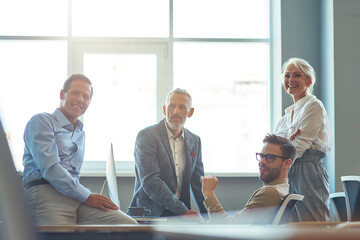 Wall Mural - Successful business team working together in the modern office, discussing something and smiling while having a meeting. Teamwork and collaboration concept