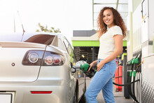 African-American Woman Filling Up Car Tank At Gas Station