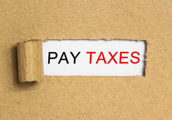 Wall Mural - The text PAY TAXES behind torn brown paper. Business Concept image