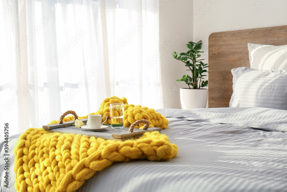 Knitted plaid with breakfast on bed at home