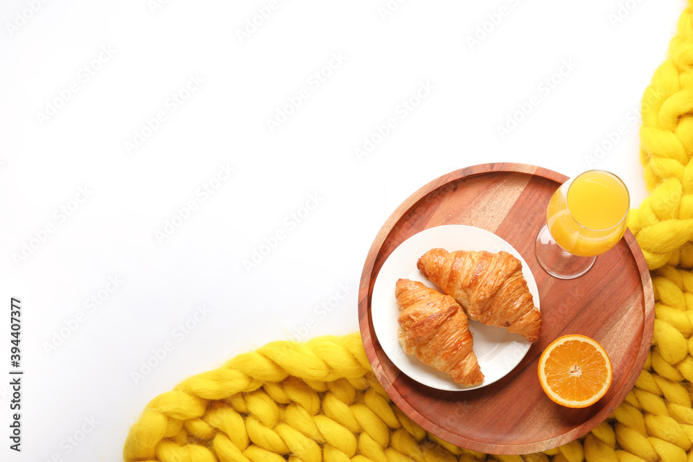 Tray with tasty breakfast and knitted plaid on white background