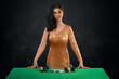 © Aliaksandr Marko - A beautiful brunette girl in a golden shiny croupier dress, stands in front of a gambling table. Casino concept, gambling.