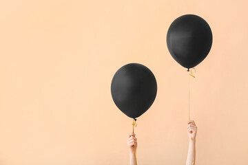 Female hands with black air balloons on color background