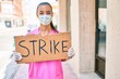 Young doctor woman wearing medical mask and holding strike banner cardboard at street of city.