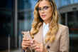 © Minerva Studio - Smiling businesswoman using a smartphone outdoor