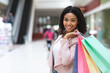 Portrait of beautiful black woman posing with shopping bags in department store