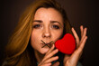 © rubchikova - Woman with closed mouth and red heart in her hands