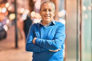 Wall Mural - senior grey-haired man with arms crossed smiling happy standing at the city.